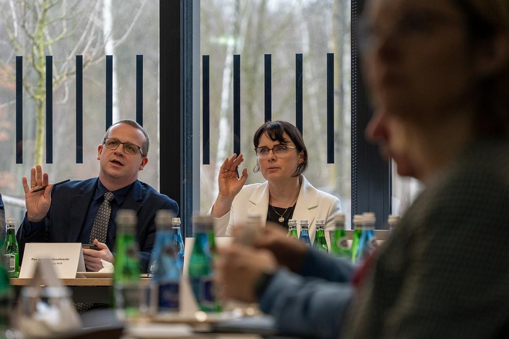 Uczestnicy posiedzenia siedzą przy stole. 