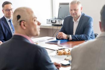 Uczestnicy spotkania siedzą przy stole. 