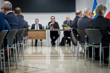 Uczestnicy spotkania siedzą przy stole. 