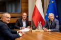 Wojciech Kamiński, Prezes Zarządu PKW S.A., Robert Kropiwnicki, Sekretarz Stanu w MAP oraz Wojciech Saługa, Marszałek Województwa Śląskiego. W tle flagi. Na stole makieta kopalni z bryłką węgla. 